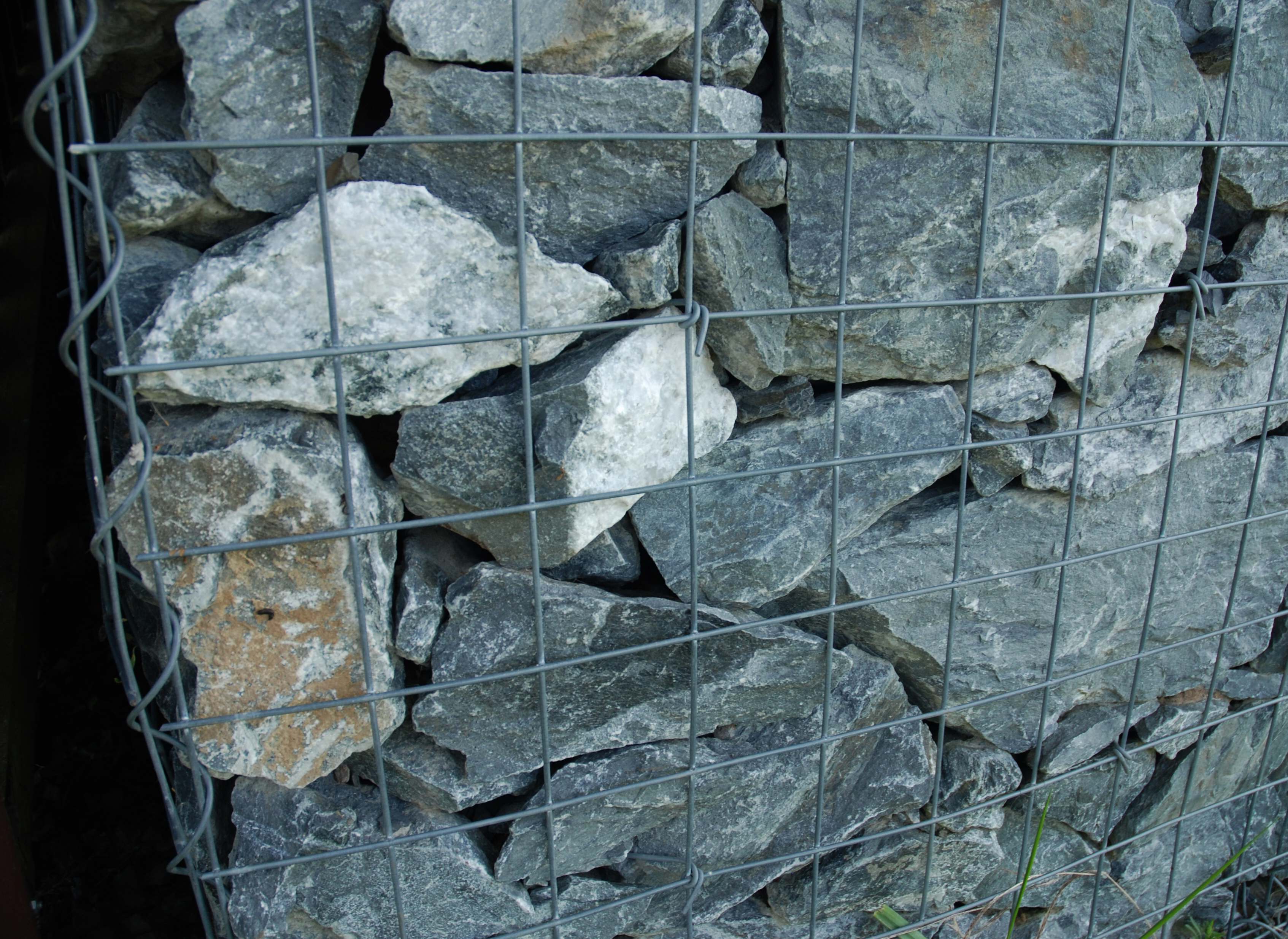 Close-up photograph of angular stones contained behind a gabion wire grid