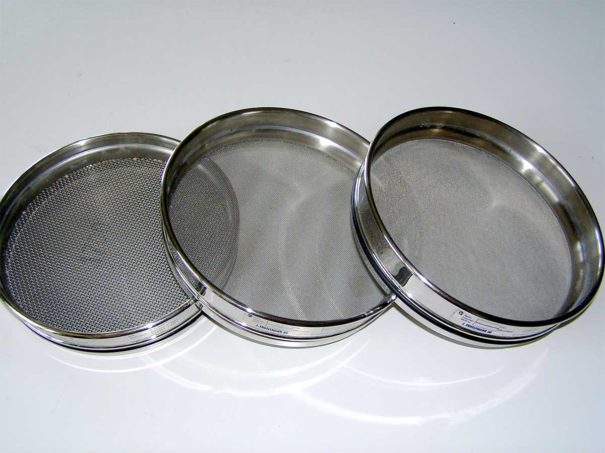 Three laboratory test sieves photographed by BMK, licensed CC BY-SA 3.0; full credit and source in the article